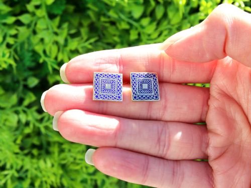 fig 2. A set of four square 18ct yellow gold cufflinks decorated with blue enamel geometric patterns, presented inside a fitted black box.