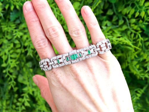 fig 1. An Art Deco platinum strap bracelet featuring geometric links set with diamonds and green accent emeralds.