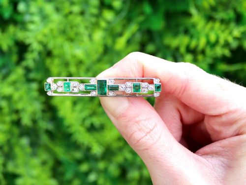 fig 1. An elongated 9ct yellow gold bar brooch featuring a central step-cut emerald flanked by geometric diamond-set panels and smaller emerald accents.