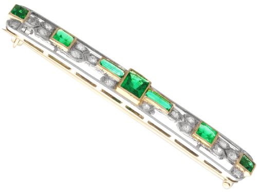 fig 3. An elongated 9ct yellow gold bar brooch featuring a central step-cut emerald flanked by geometric diamond-set panels and smaller emerald accents.