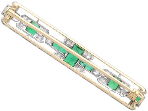 fig 4. An elongated 9ct yellow gold bar brooch featuring a central step-cut emerald flanked by geometric diamond-set panels and smaller emerald accents.