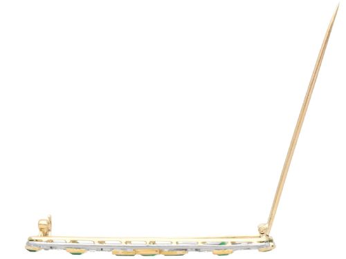fig 5. An elongated 9ct yellow gold bar brooch featuring a central step-cut emerald flanked by geometric diamond-set panels and smaller emerald accents.