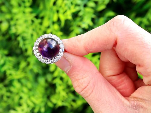 fig 1. An antique platinum dress ring set with a large central purple cabochon amethyst surrounded by a halo of round diamonds.