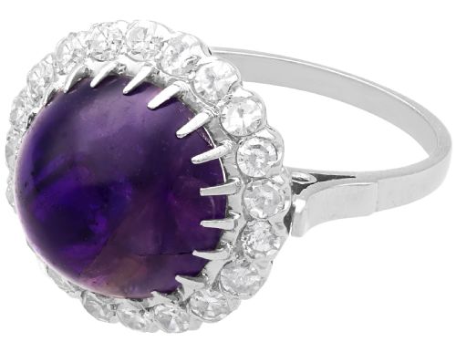 fig 2. An antique platinum dress ring set with a large central purple cabochon amethyst surrounded by a halo of round diamonds.