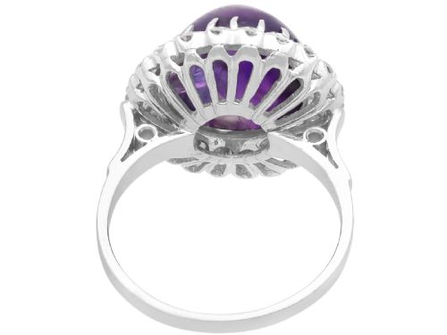 fig 3. An antique platinum dress ring set with a large central purple cabochon amethyst surrounded by a halo of round diamonds.