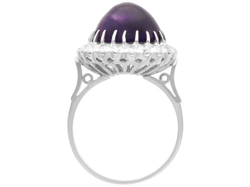 fig 4. An antique platinum dress ring set with a large central purple cabochon amethyst surrounded by a halo of round diamonds.