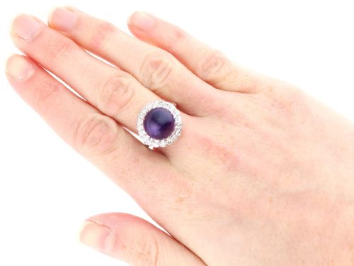 fig 6. An antique platinum dress ring set with a large central purple cabochon amethyst surrounded by a halo of round diamonds.