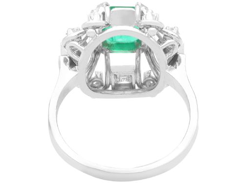 fig 3. An Art Deco 18ct white gold ring featuring a central octagonal green emerald surrounded by geometric diamond-set loop mounts.
