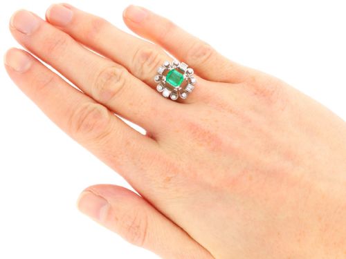 fig 5. An Art Deco 18ct white gold ring featuring a central octagonal green emerald surrounded by geometric diamond-set loop mounts.