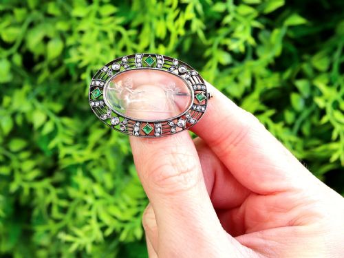 fig 1. An oval Victorian brooch featuring a reverse-carved rock crystal intaglio depicting Cupid and Psyche, bordered by rose-cut diamonds and square-cut emeralds set in gold and silver.