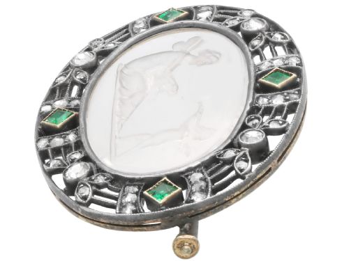 fig 4. An oval Victorian brooch featuring a reverse-carved rock crystal intaglio depicting Cupid and Psyche, bordered by rose-cut diamonds and square-cut emeralds set in gold and silver.