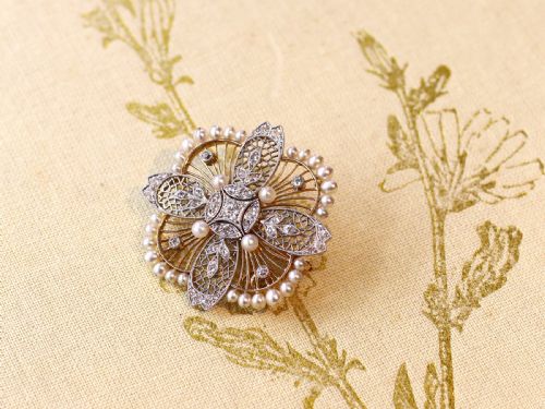 fig 2. An openwork circular Edwardian floral pendant brooch crafted in rose gold and platinum, set with central diamonds and a perimeter of natural pearls.
