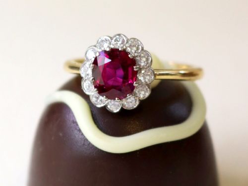 fig 2. An 18ct yellow gold cluster ring featuring a central cushion cut red ruby framed by a halo of round diamonds.
