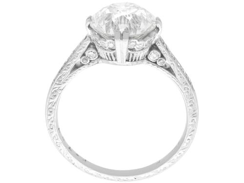 fig 4. A platinum solitaire ring featuring a large round diamond secured by multi-claw prongs on a hand-engraved decorative band.