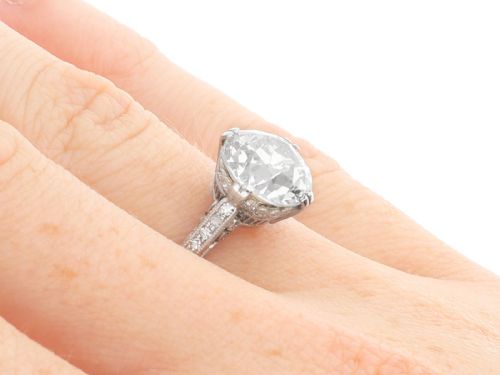fig 6. A platinum solitaire ring featuring a large round diamond secured by multi-claw prongs on a hand-engraved decorative band.