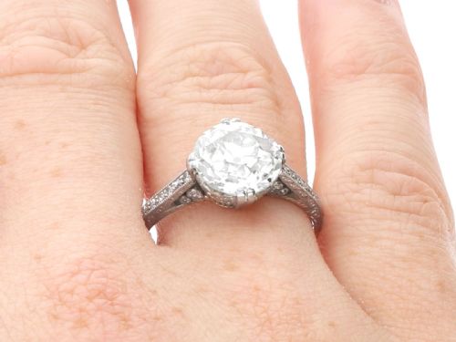 fig 7. A platinum solitaire ring featuring a large round diamond secured by multi-claw prongs on a hand-engraved decorative band.
