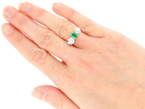 fig 6. An Art Deco platinum trilogy ring featuring a central emerald-cut green emerald flanked by two round diamonds.