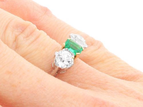 fig 7. An Art Deco platinum trilogy ring featuring a central emerald-cut green emerald flanked by two round diamonds.