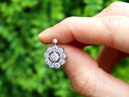 fig 1. A pair of Art Deco 18ct white gold drop earrings featuring a circular diamond cluster motif suspended from a single bezel-set diamond surmount.