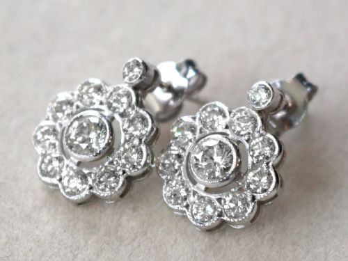 fig 2. A pair of Art Deco 18ct white gold drop earrings featuring a circular diamond cluster motif suspended from a single bezel-set diamond surmount.
