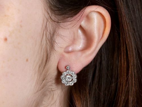 fig 7. A pair of Art Deco 18ct white gold drop earrings featuring a circular diamond cluster motif suspended from a single bezel-set diamond surmount.