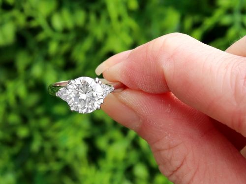 fig 1. A vintage platinum ring featuring a large round brilliant central diamond flanked by two triangular side diamonds on a smooth metal band.