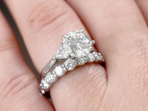fig 3. A vintage platinum ring featuring a large round brilliant central diamond flanked by two triangular side diamonds on a smooth metal band.