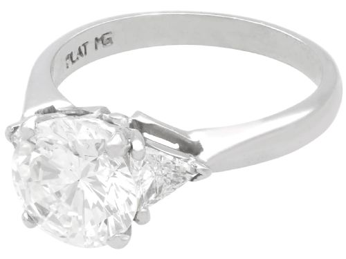 fig 5. A vintage platinum ring featuring a large round brilliant central diamond flanked by two triangular side diamonds on a smooth metal band.