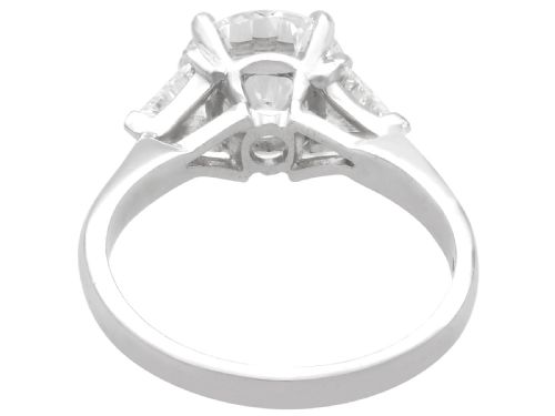 fig 6. A vintage platinum ring featuring a large round brilliant central diamond flanked by two triangular side diamonds on a smooth metal band.