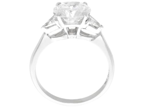 fig 7. A vintage platinum ring featuring a large round brilliant central diamond flanked by two triangular side diamonds on a smooth metal band.