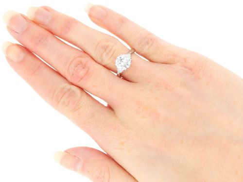fig 8. A vintage platinum ring featuring a large round brilliant central diamond flanked by two triangular side diamonds on a smooth metal band.