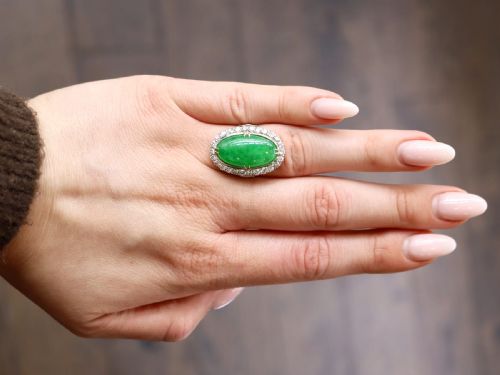 fig 2. An antique Edwardian ring featuring a large oval green jadeite cabochon encircled by a halo of round diamonds on a gold band.