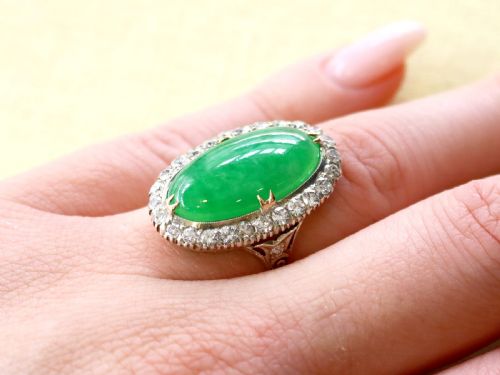 fig 3. An antique Edwardian ring featuring a large oval green jadeite cabochon encircled by a halo of round diamonds on a gold band.