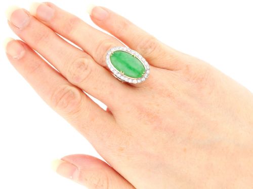fig 7. An antique Edwardian ring featuring a large oval green jadeite cabochon encircled by a halo of round diamonds on a gold band.