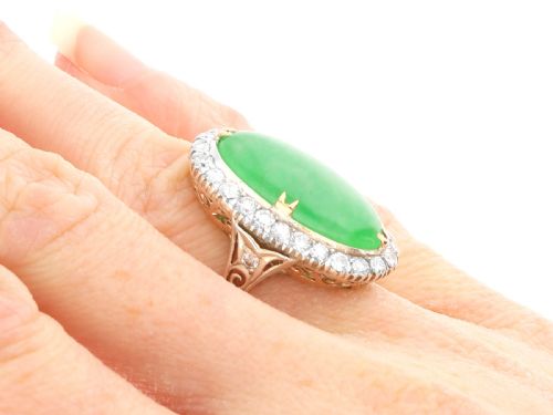fig 8. An antique Edwardian ring featuring a large oval green jadeite cabochon encircled by a halo of round diamonds on a gold band.