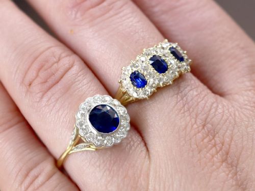 fig 3. An antique 18ct yellow gold ring featuring a central round blue sapphire encircled by a halo of bright diamonds set within a scalloped millegrain bezel.