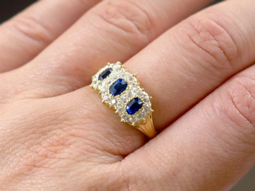 fig 2. An antique 18ct yellow gold ring featuring three rectangular cushion-cut blue sapphires surrounded by a halo of old-cut diamonds.