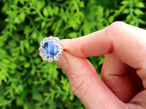 fig 1. An antique Art Deco ring featuring a cushion-cut blue sapphire central stone surrounded by a cluster halo of round diamonds set on a yellow gold band.