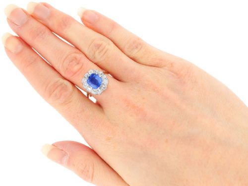 fig 7. An antique Art Deco ring featuring a cushion-cut blue sapphire central stone surrounded by a cluster halo of round diamonds set on a yellow gold band.