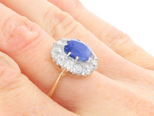fig 8. An antique Art Deco ring featuring a cushion-cut blue sapphire central stone surrounded by a cluster halo of round diamonds set on a yellow gold band.