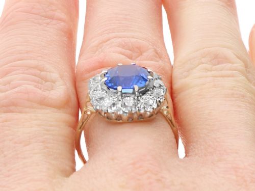 fig 9. An antique Art Deco ring featuring a cushion-cut blue sapphire central stone surrounded by a cluster halo of round diamonds set on a yellow gold band.