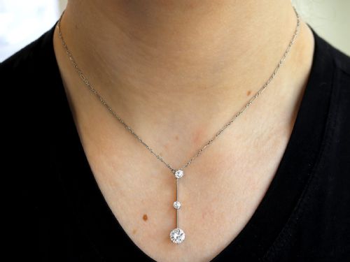 fig 2. An 18ct white gold Art Deco pendant featuring three linear claw-set round diamonds suspended on a delicate chain.