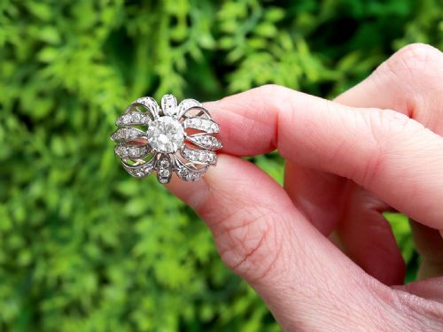 fig 1. A platinum dress ring featuring a central round brilliant cut diamond surrounded by openwork diamond-set petal motifs.