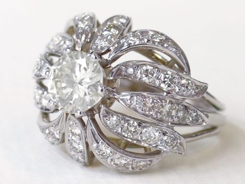 fig 3. A platinum dress ring featuring a central round brilliant cut diamond surrounded by openwork diamond-set petal motifs.