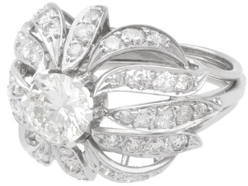 fig 4. A platinum dress ring featuring a central round brilliant cut diamond surrounded by openwork diamond-set petal motifs.