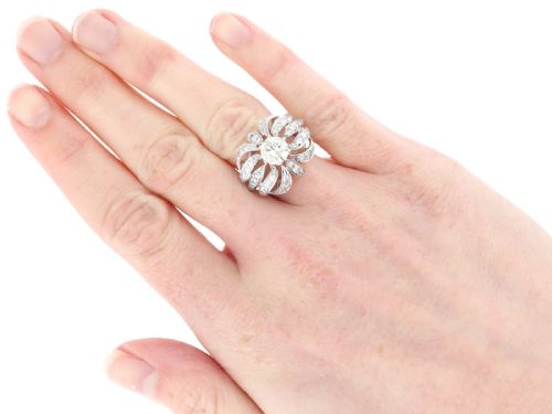 fig 7. A platinum dress ring featuring a central round brilliant cut diamond surrounded by openwork diamond-set petal motifs.
