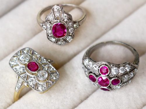 fig 2. An Art Deco 14ct yellow gold dress ring featuring a central oval red ruby set within a rectangular pierced openwork plaque adorned with round diamonds and millegrain edging.