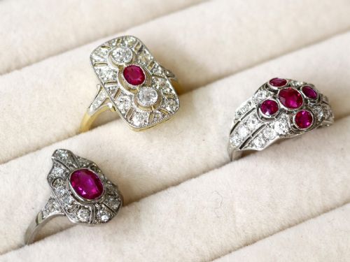 fig 3. An Art Deco 14ct yellow gold dress ring featuring a central oval red ruby set within a rectangular pierced openwork plaque adorned with round diamonds and millegrain edging.