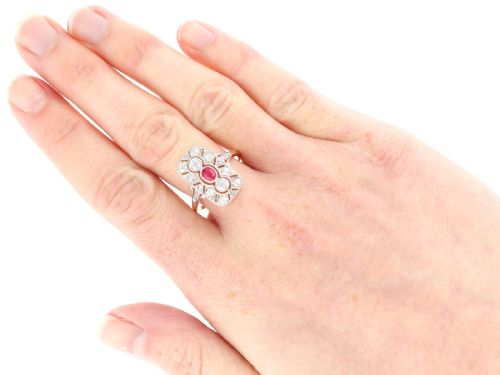fig 8. An Art Deco 14ct yellow gold dress ring featuring a central oval red ruby set within a rectangular pierced openwork plaque adorned with round diamonds and millegrain edging.