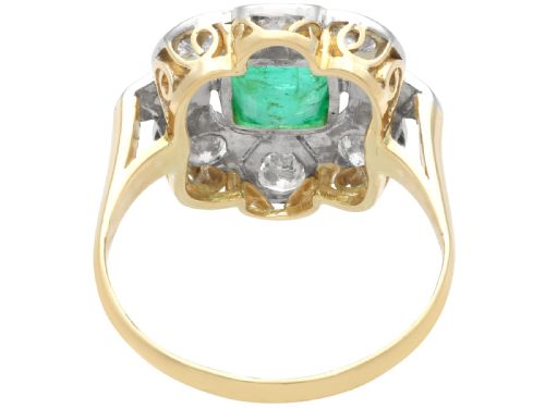 fig 5. An Art Deco dress ring featuring a central cushion-cut green emerald surrounded by a geometric pierced diamond halo set in white metal on an 18ct yellow gold band.